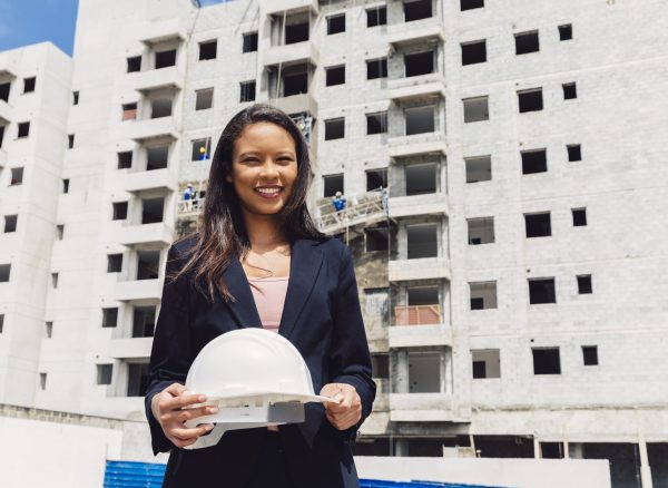 happy-african-american-lady-holding-safety-helmet-near-building-construction